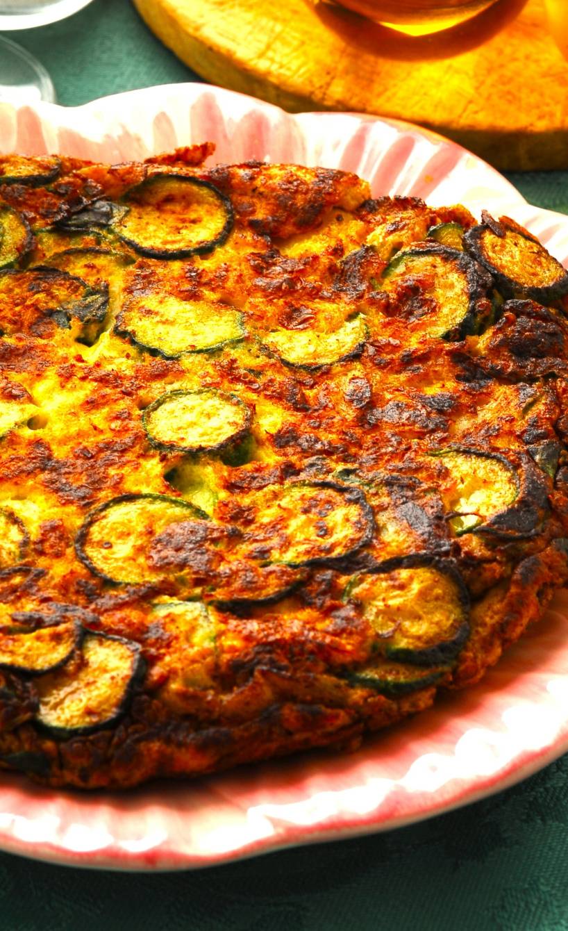 Frittata di Zucchine auf einem Teller, daneben Olivenöl in einer Karaffe