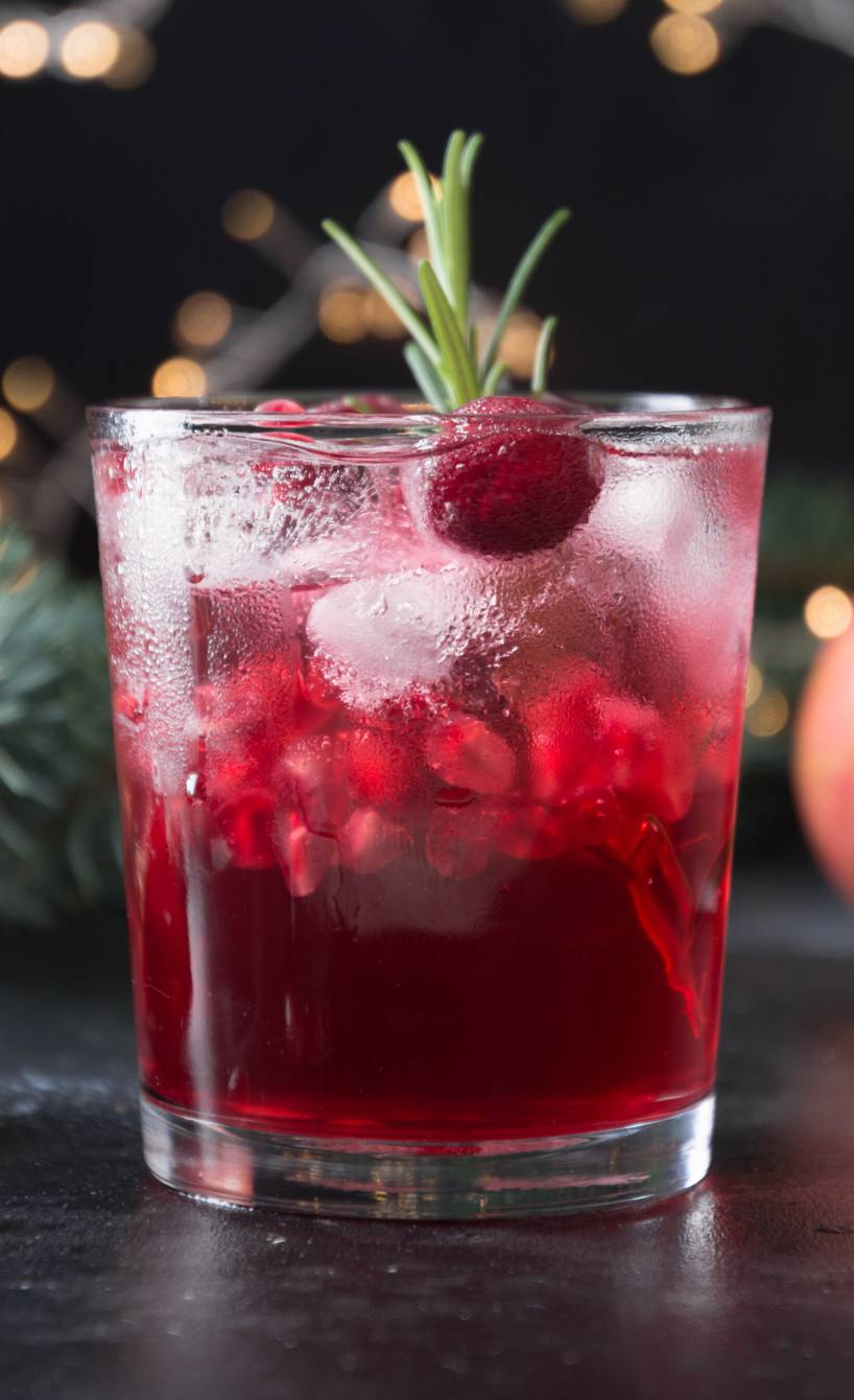 Prosecco-Cocktail mit Granatapfel in einem Cocktailglas auf einem festlich gedeckten Tisch