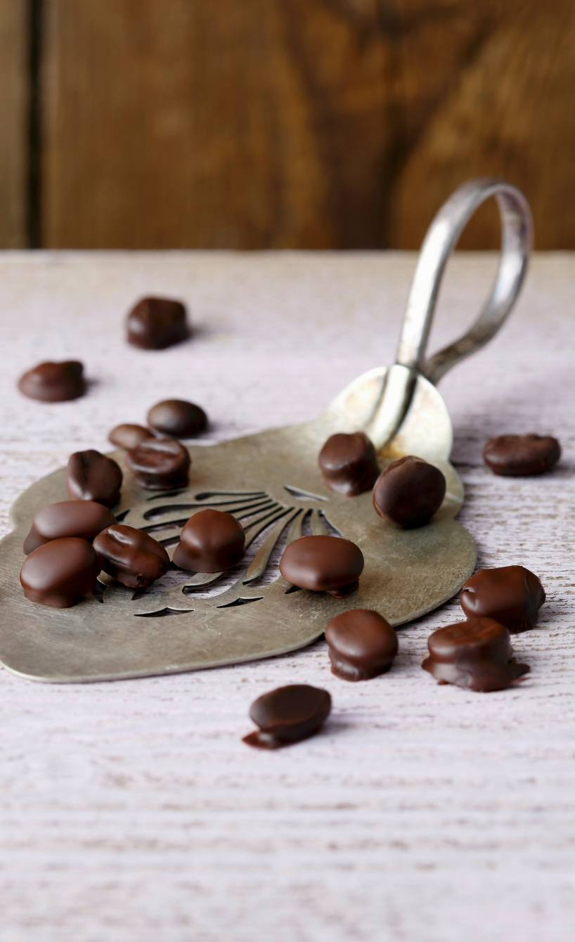 Schokolierte Espressobohnen auf einer antiken Kuchenschaufel angerichtet auf einem Tisch