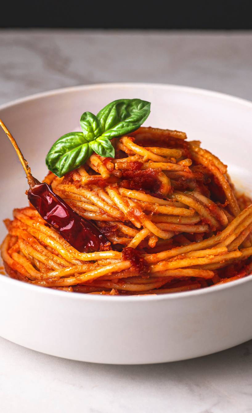 Spaghetti all’assassina in einer weißen Schale, getoppt mit einer getrockneten Chili und Basilikum