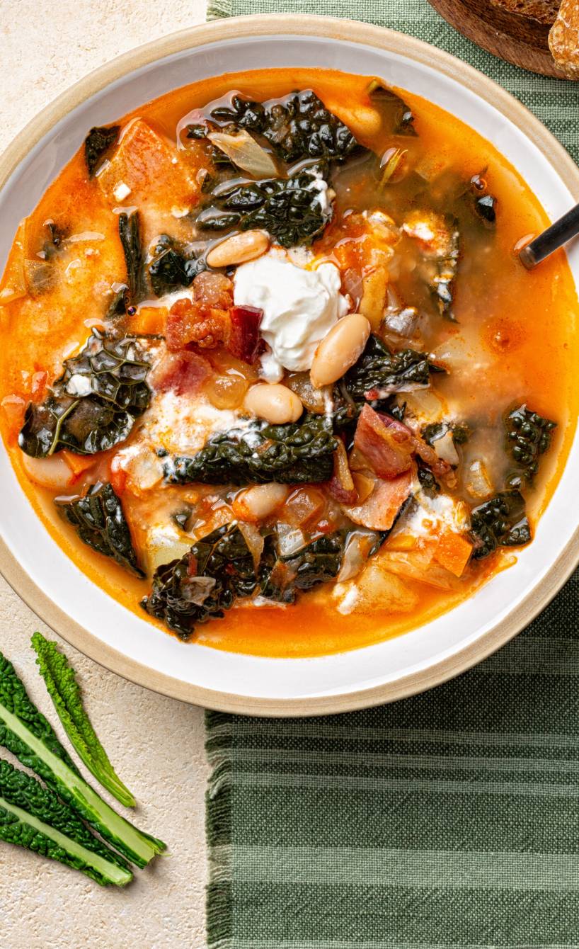 Zuppa Toscana, italienische Brotsuppe in einem Suppenteller, daneben aufgeschnittenes Ciabatta