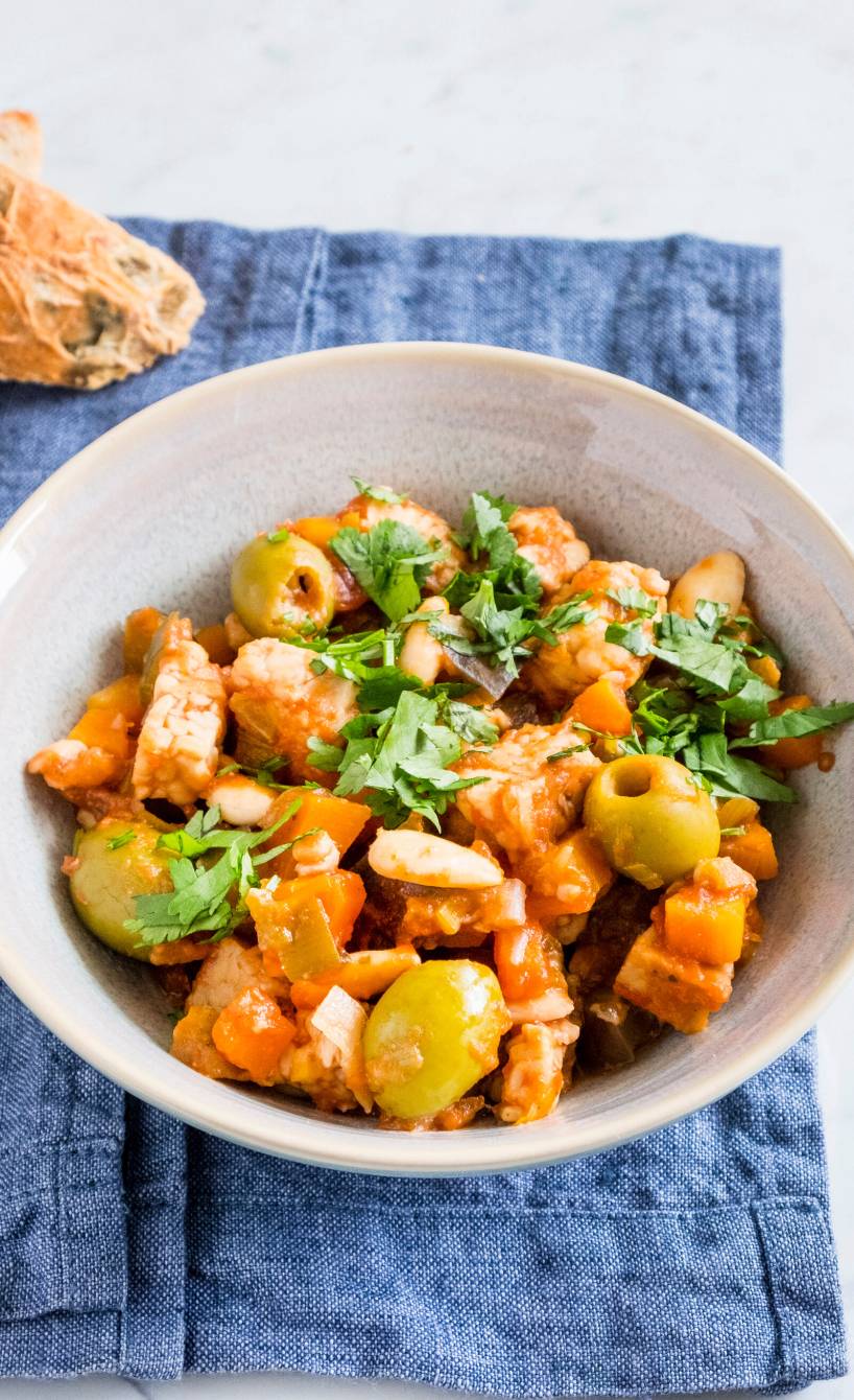 Tempeh Caponata auf einem Teller, daneben zwei Scheiben Baguette