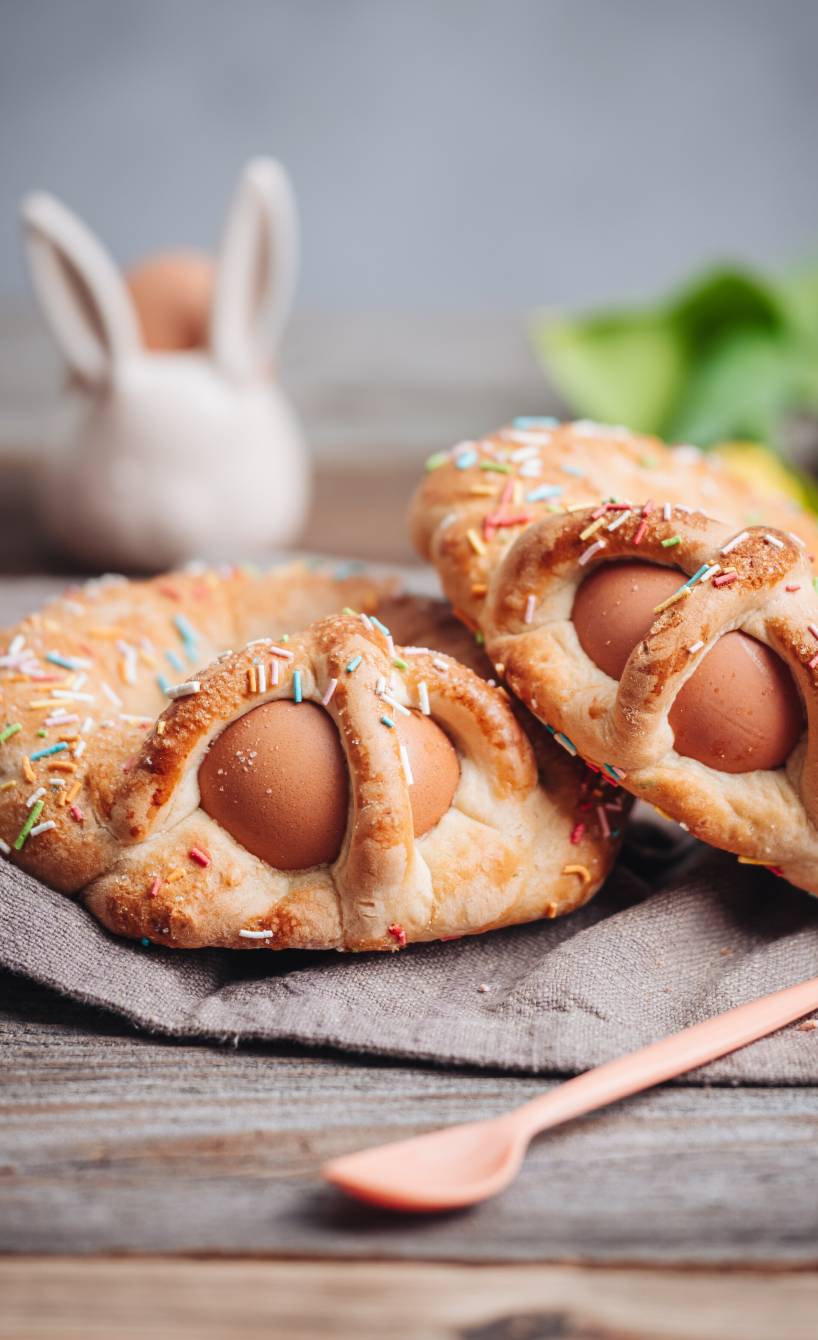 Zwei Scarcella Osternester mit gekochtem Ei und bunten Streuseln auf einem Leinentuch