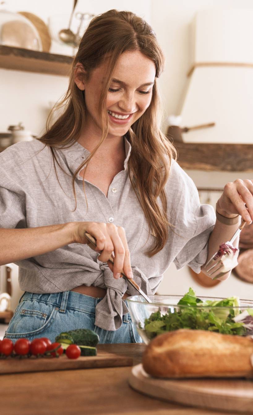Junge Frau bereitet veganes Gericht in ihrer Küche zu