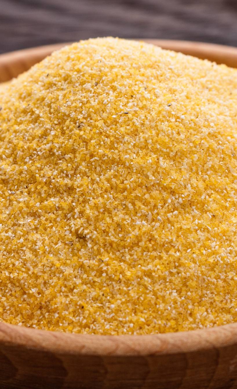 Maisgrieß für Polenta in einer Holzschale auf einem Holztisch