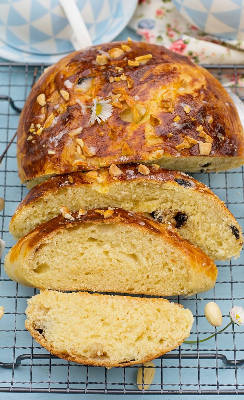 Osterbrot mit Rosinen und Mandeln bestreut angeschnitten auf einem Kuchengitter