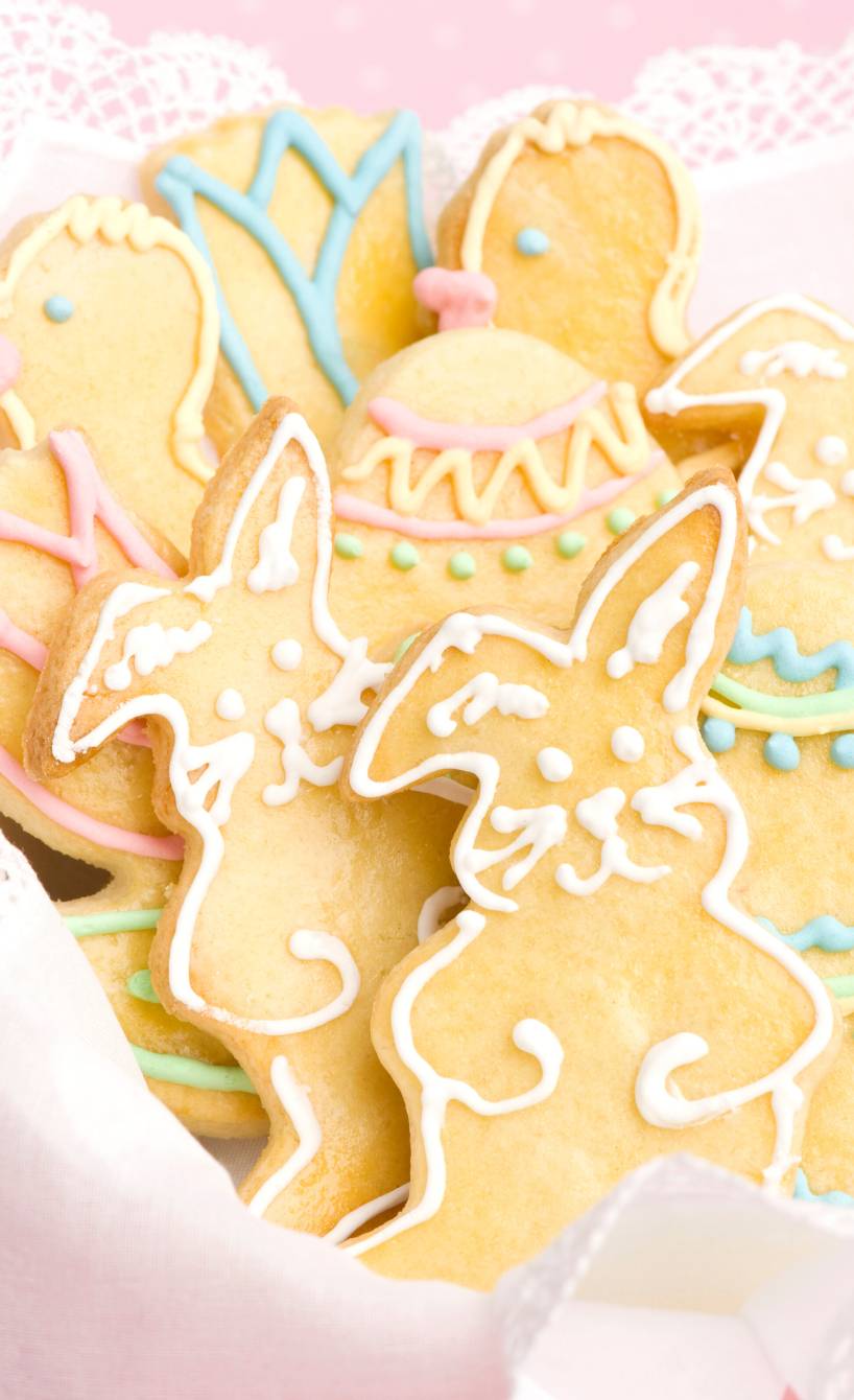 Verzierte Osterkekse in Form von Ostereiern, Hasen und Enten in einem Körbchen