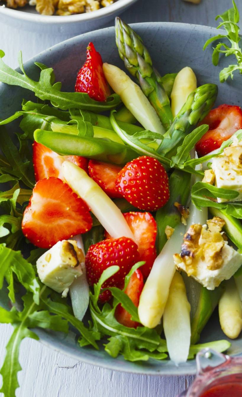 Salat mit gekochtem grünem und weißem Spargel und Erdbeeen in einer Schüssel