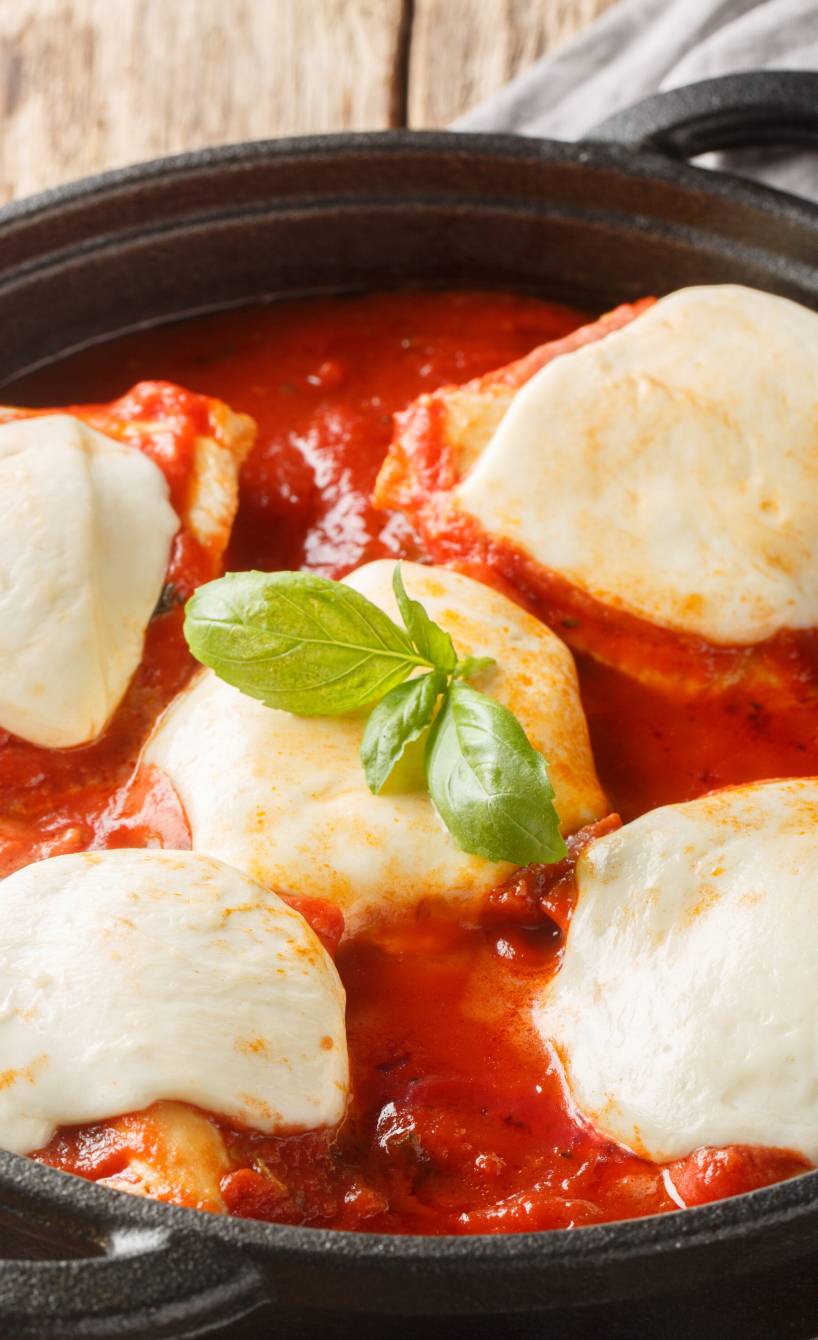 Überbackenes Tomate-Mozzarella-Hähnchen alla Pizzaiola in einer Pfanne garniert mit frischem Basilikum