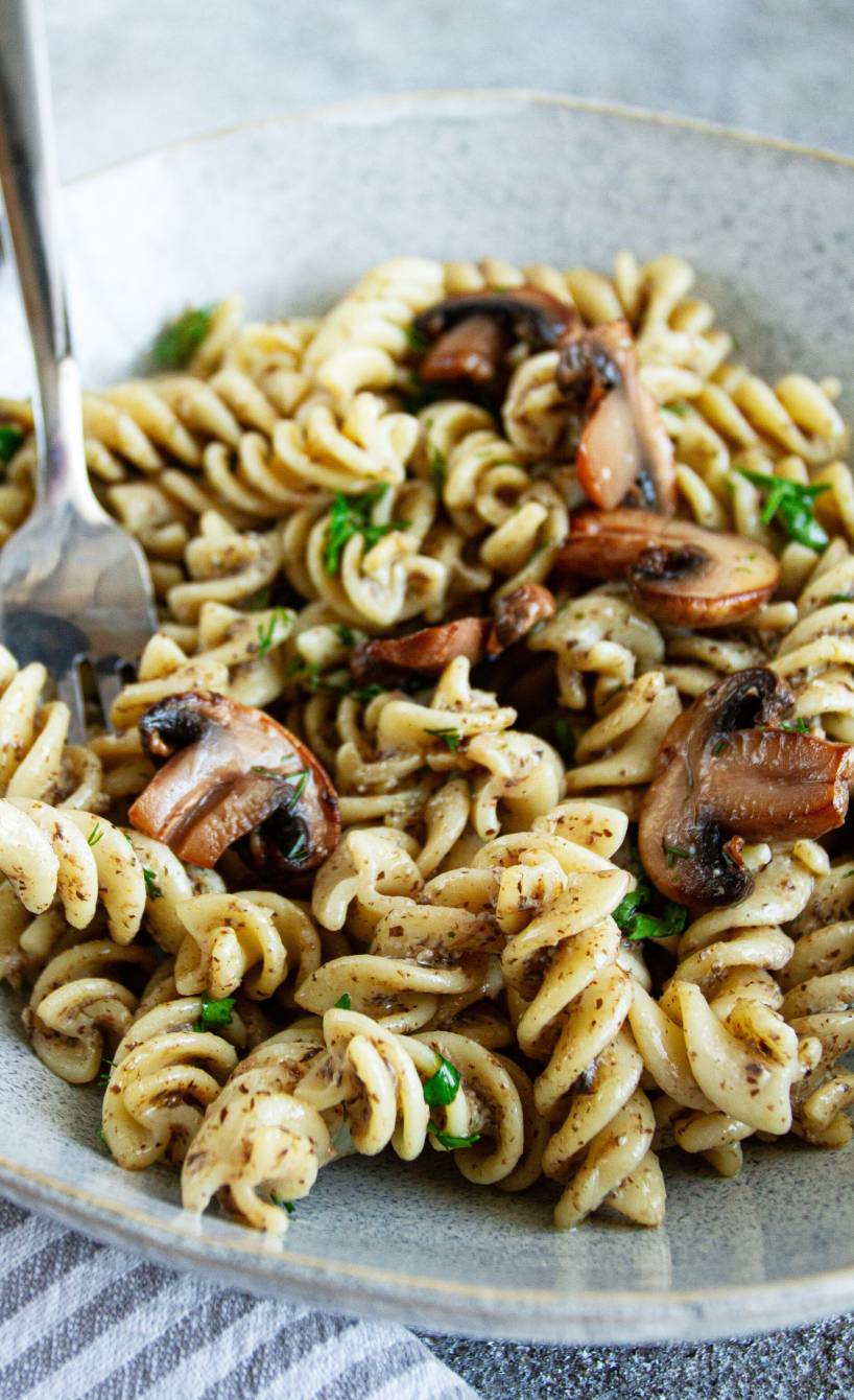 Fusilli mit vegetarischer Carbonara aus Tofu und Pilzen auf einem Teller garniert mit frischer Petersilie