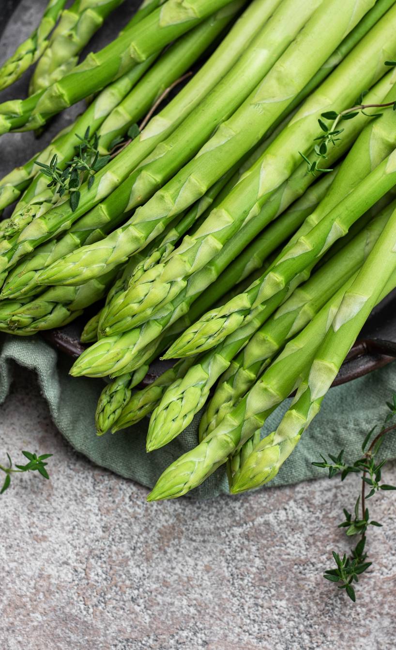 Ein Pfund grüner Spargel auf einem Teller, daneben Gewürze in einer Küche