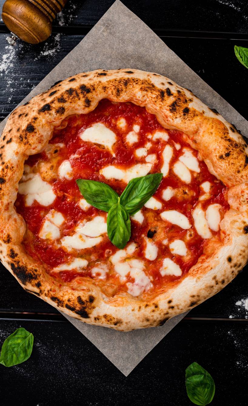 Pizza Napoletana mit Basilikum garniert auf einem Stück Backpapier