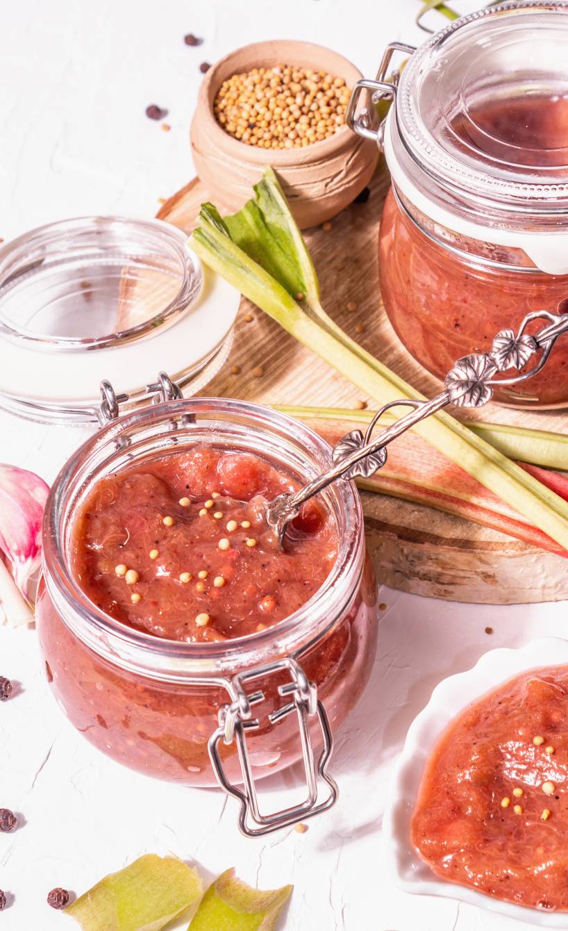 Rhabarber-Senf in zwei offenen Einmachgläsern getoppt mit Senfkörnern