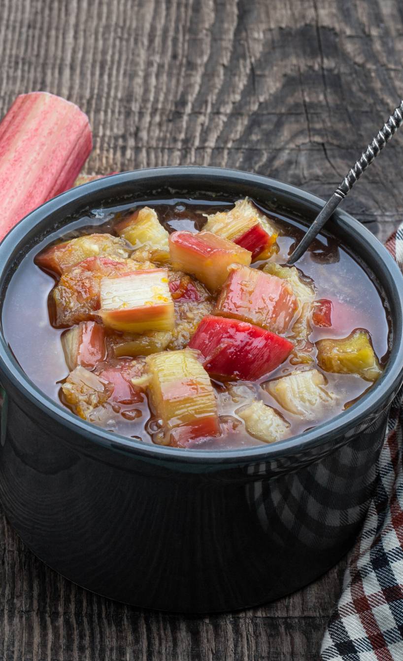 Selbst gekochtes Rhabarberkompott in einer Steingutschale auf einem Holztisch