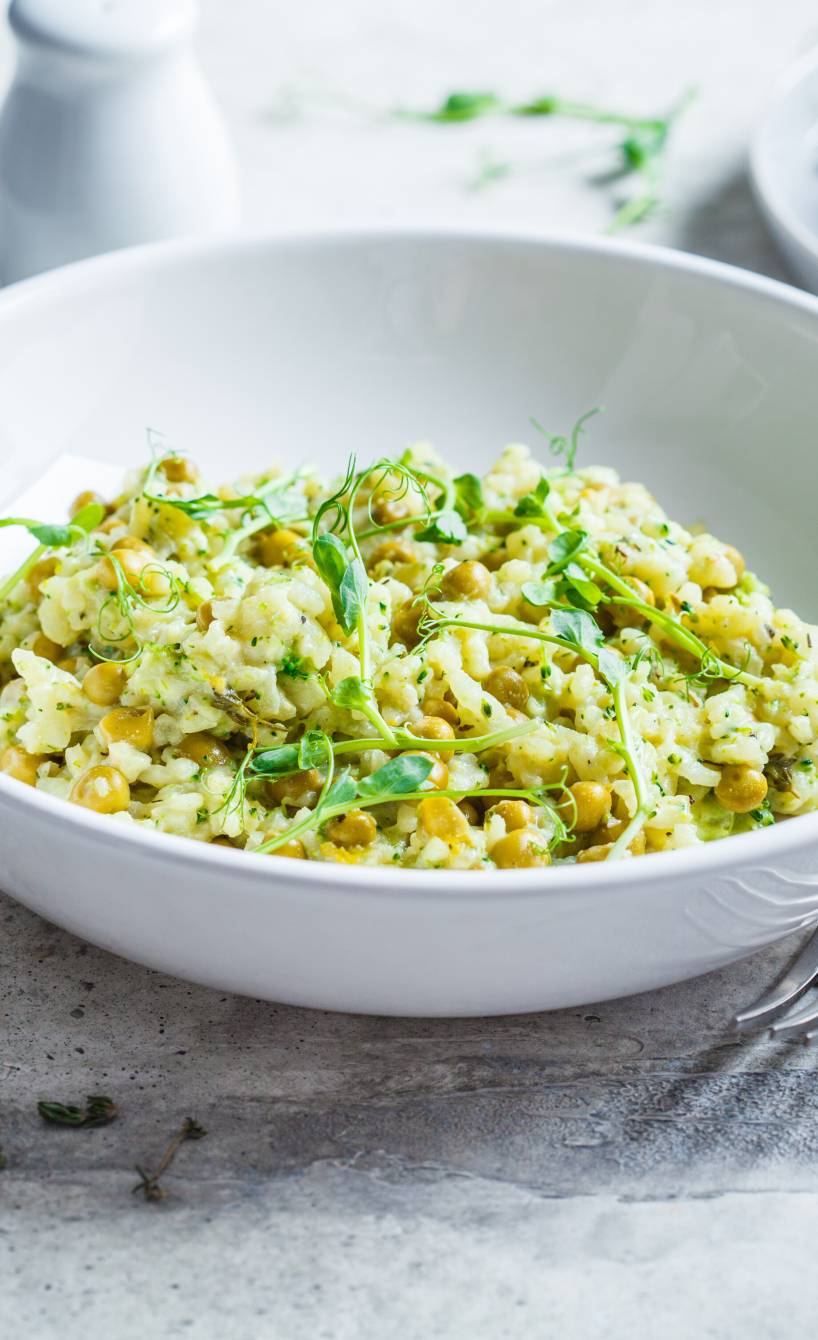 Risi e Bisi Reis mit Erbsen und Parmesan auf einem tiefen Teller garniert mit frischen Kräutern