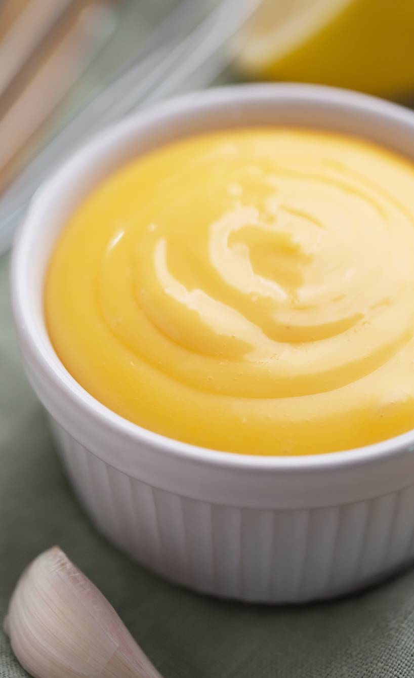 selbst gemachtes Aioli in einer kleinen Schale, daneben Zitrone und Knoblauch