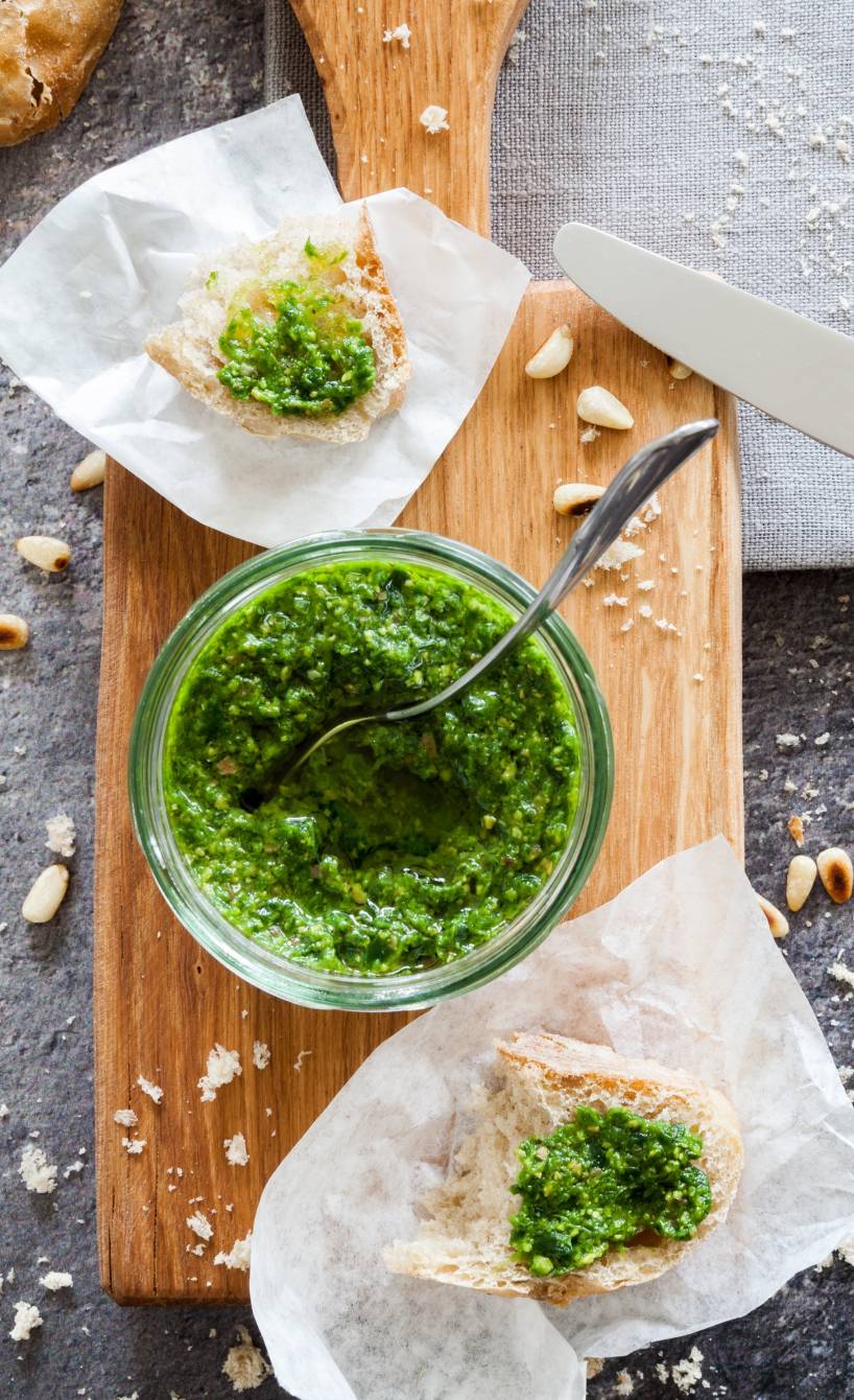 Selbstgemachtes Bärlauchpesto in einem Weckglas, daneben ein Stück Ciabatta, das damit bestrichen wurde
