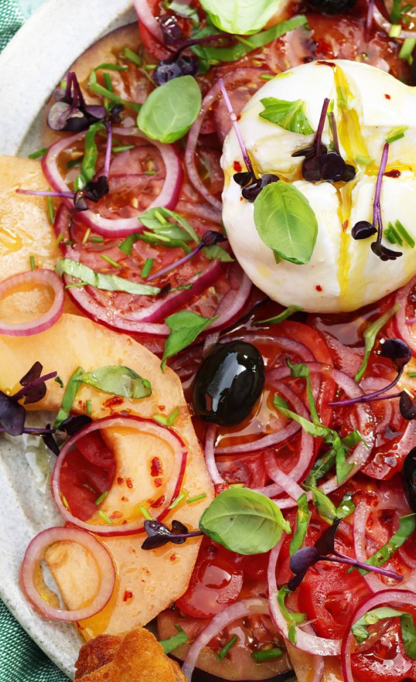 Burrata auf Tomaten-Melonen-Carpaccio auf einem Teller
