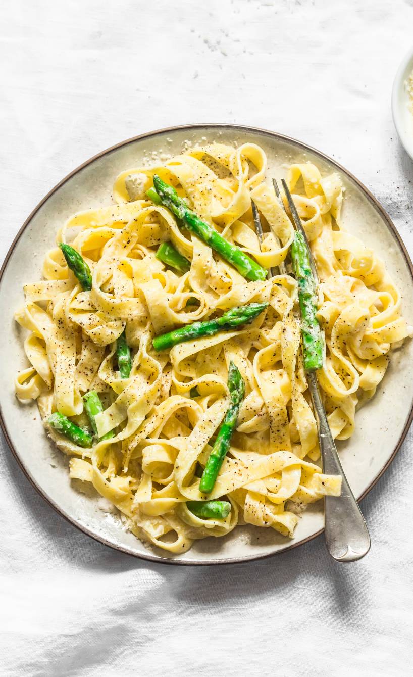 One Pot Spargel Pasta auf einem Teller, daneben ein Schälchen Parmesan