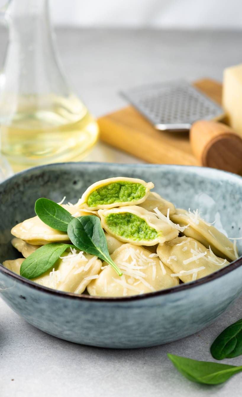 Ravioli mit Ricotta-Spinat-Füllung in einer Schüssel, einige davon halbiert mit gut sichtbarer Füllung