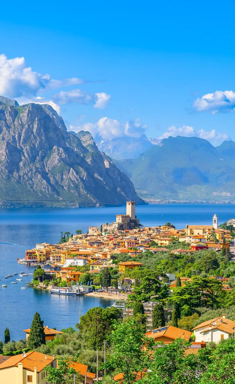 Blick über die Stadt Malescine, den Gardasee, blühende Bäume und Berge