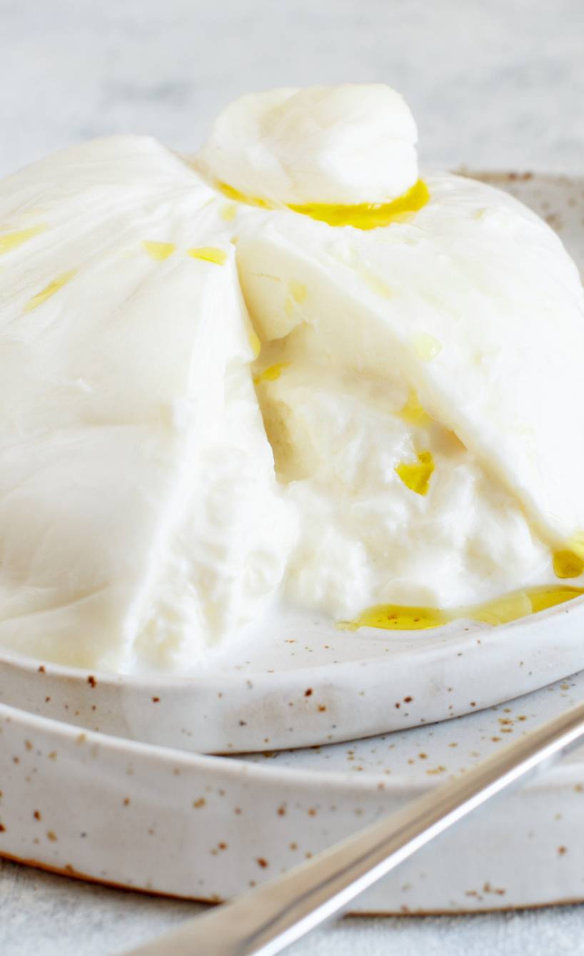 Burrata aufgeschnitten auf einem Teller übergossen mit Olivenöl