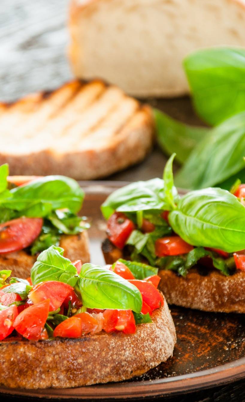 Mehrere klassiches Bruschetta angerichtet auf einem Tisch neben weiteren kalten Antipasti Mehrere klassiches Bruschetta angerichtet auf einem Tisch neben weiteren kalten Antipasti