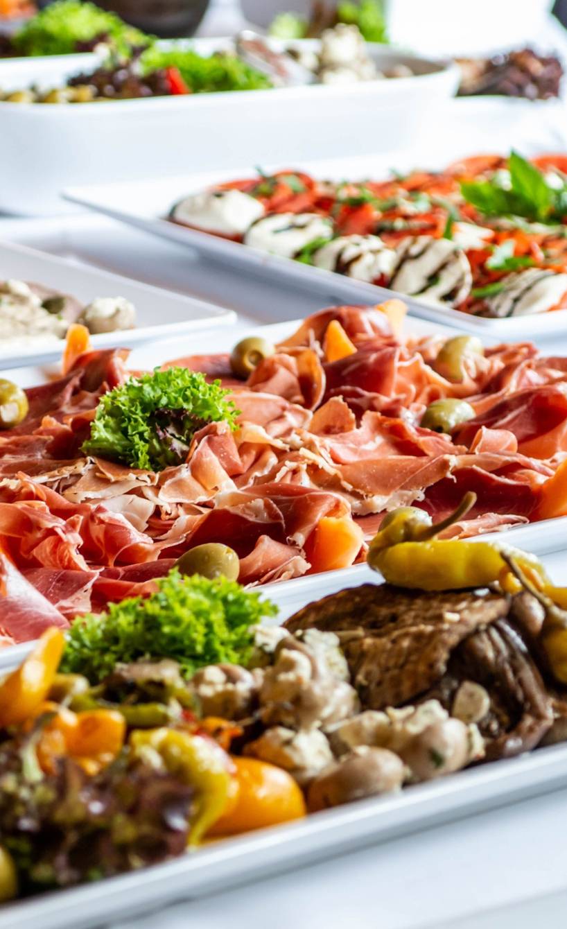 Buffet mit Platten mit verschiedenem kaltem Fingerfood und Antipasti arrangiert auf einem langen Tisch