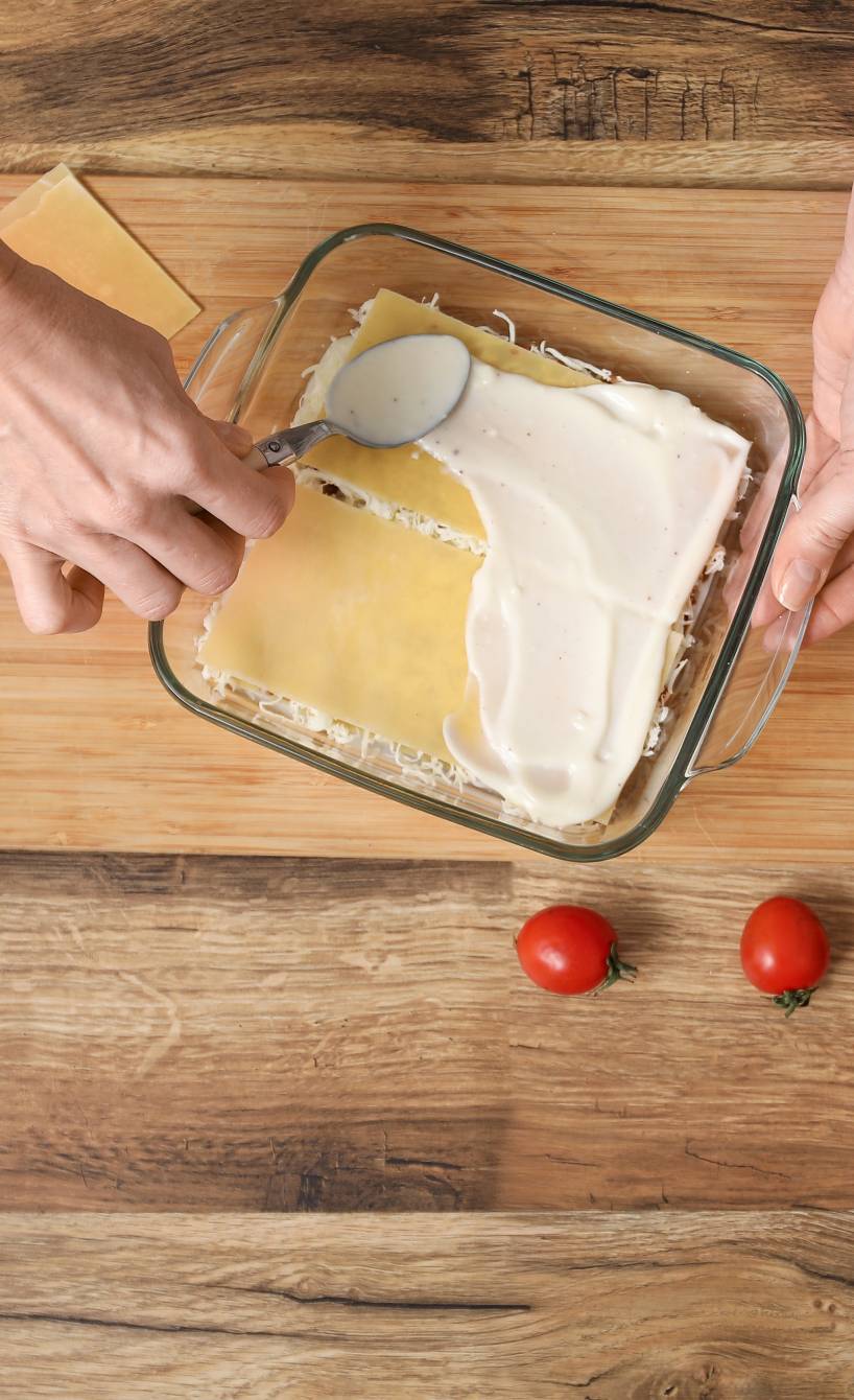 Hackfleisch, Käse und Gewürze auf einem Tisch, auf dem gerade Lasagne geschichtet wird