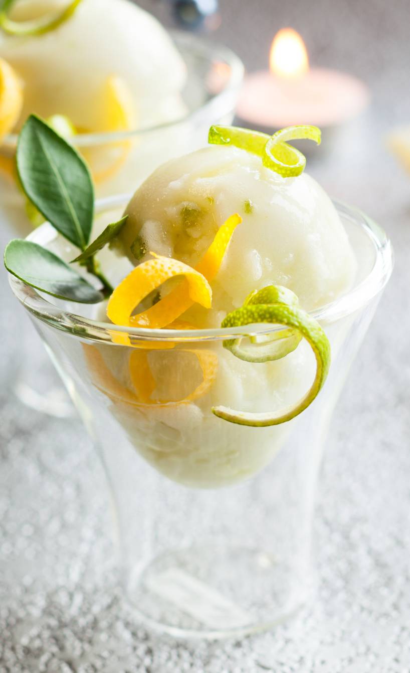 Selbstgemachtes Limoncello Sorbet in zwei Eisbechern dekoriert mit Minze und Zitrone
