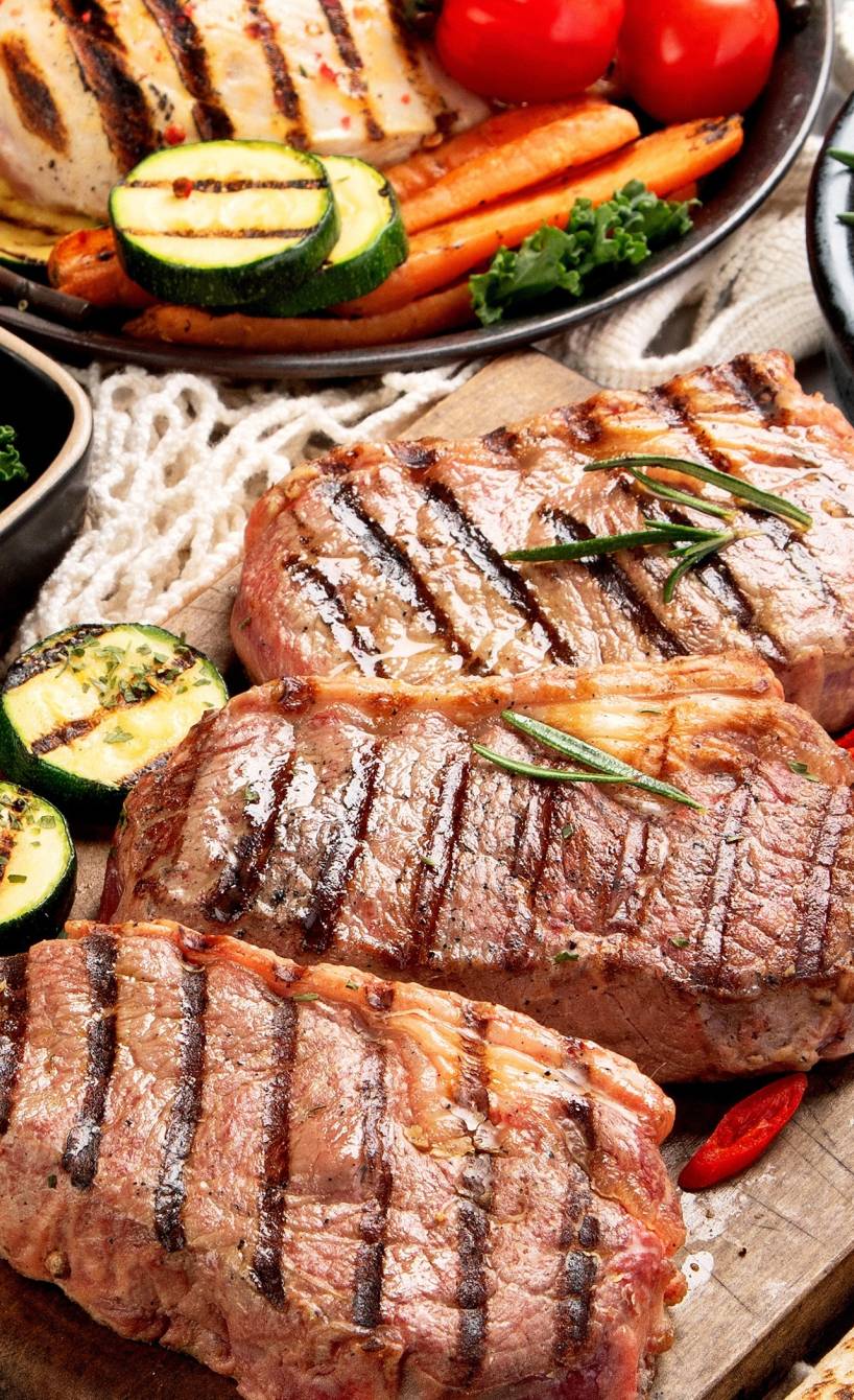 Esstisch mit Fleisch, Fisch, Brot und Gemüse vom Grill