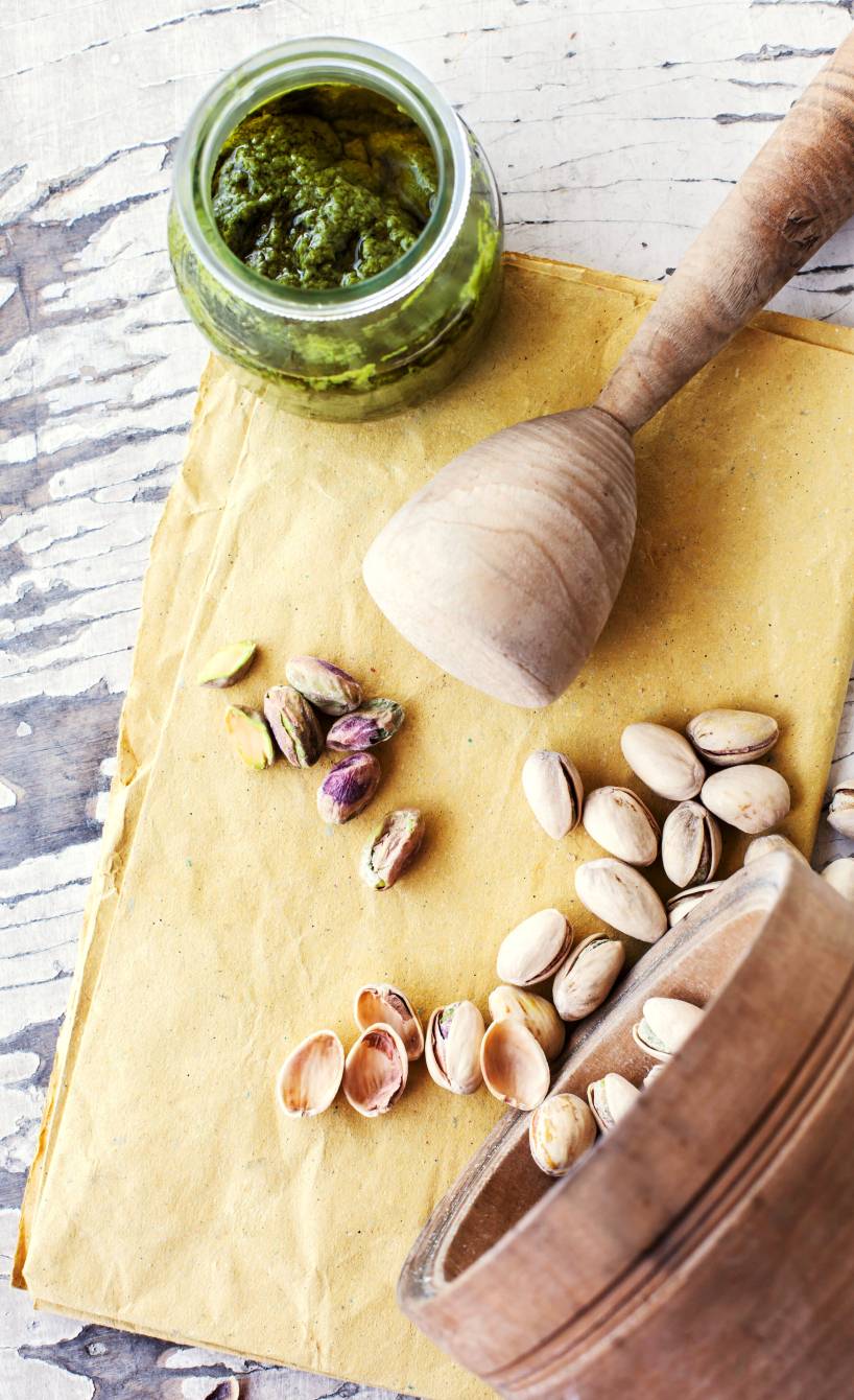 Selbst gemachtes Pistazienpesto in einem Glas, daneben Pistazien auf einem Tisch