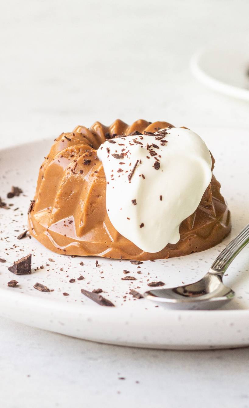 Selbst gemachtes Schoko-Panna Cotta auf einem Dessertteller getoppt von Sahne und Minzblättern