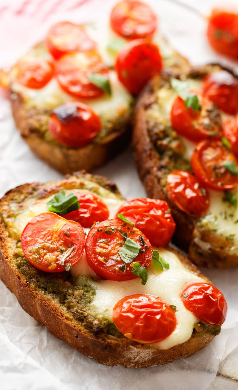 Drei Bruschettas mit geschmolzenem Mozzarella und Tomaten auf einem Teller Drei Bruschettas mit geschmolzenem Mozzarella und Tomaten auf einem Teller
