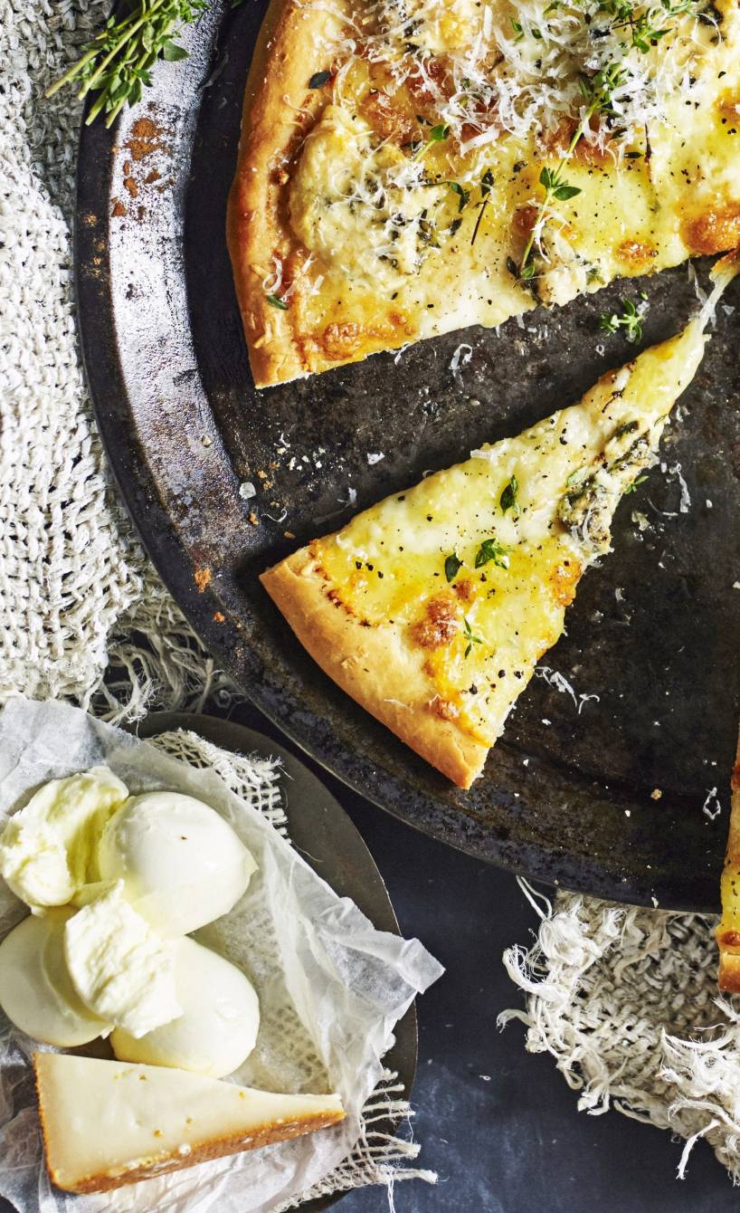 Pizza mit vier Käsesorten, daneben frischer Käse