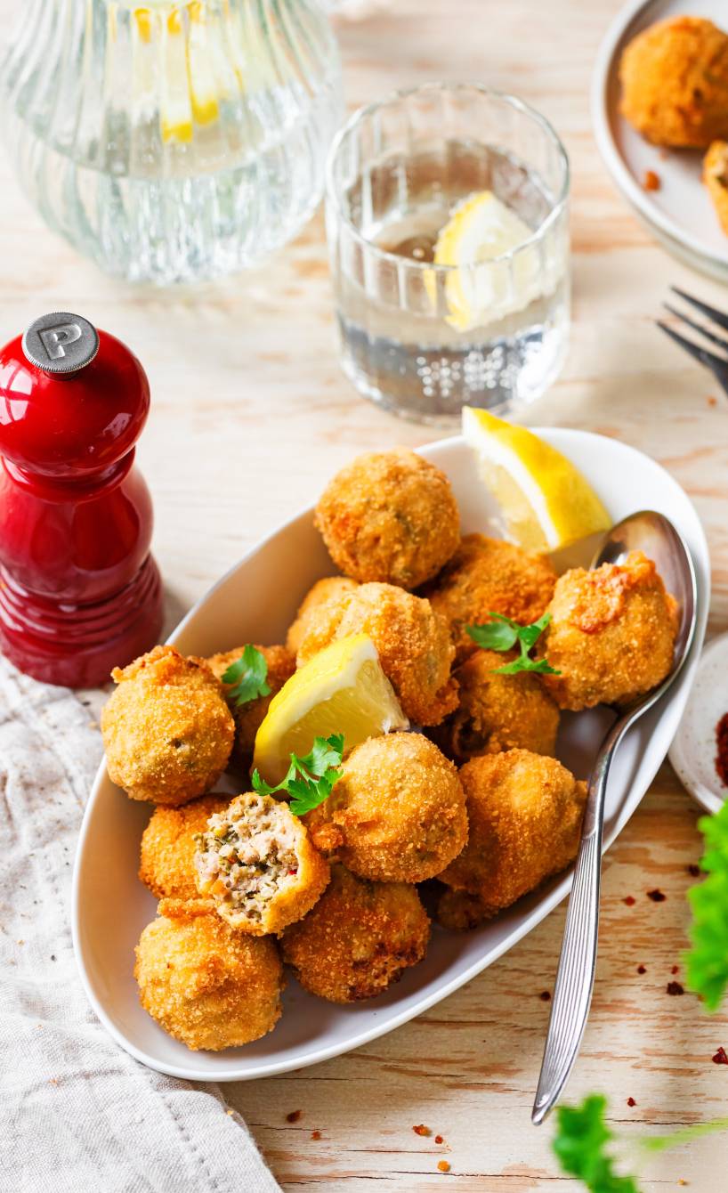 Mehrere Polpettine di Tonno frittierte Thunfischbällchen in einer Vorspeisenschale garniert mit Zitronenspalten