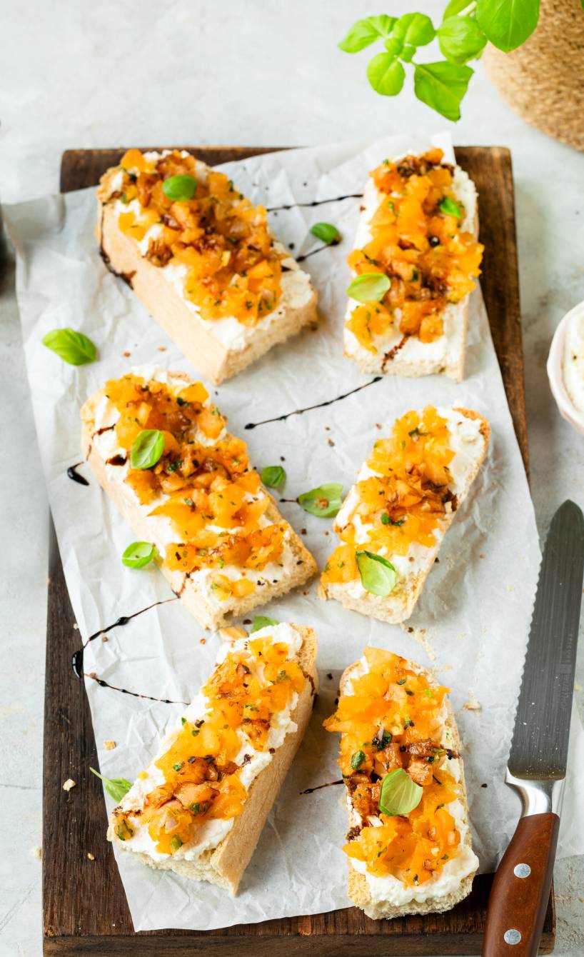 Fünf Melonen-Bruschetta mit Feta-Creme angerichtet auf einem Holzbrett