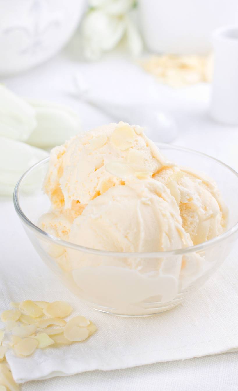 Drei Kugeln Low-Carb-Vanille-Mandel-Eis in einem Glasschälchen getoppt mit Mandelblättchen