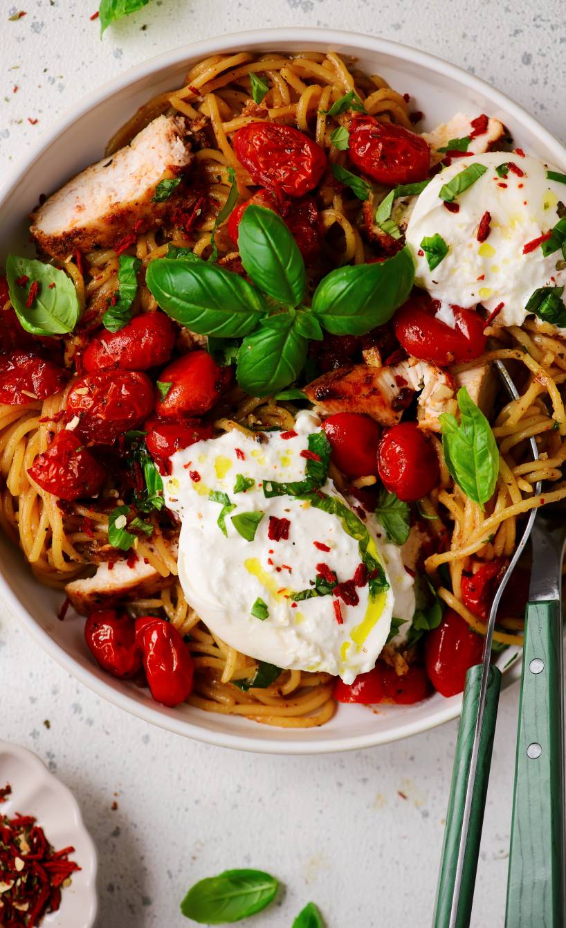 One-pot-Spaghetti mit Hähnchen, Cherrytomaten, getoppt von Burrata und Basilikum in einem tiefen Teller