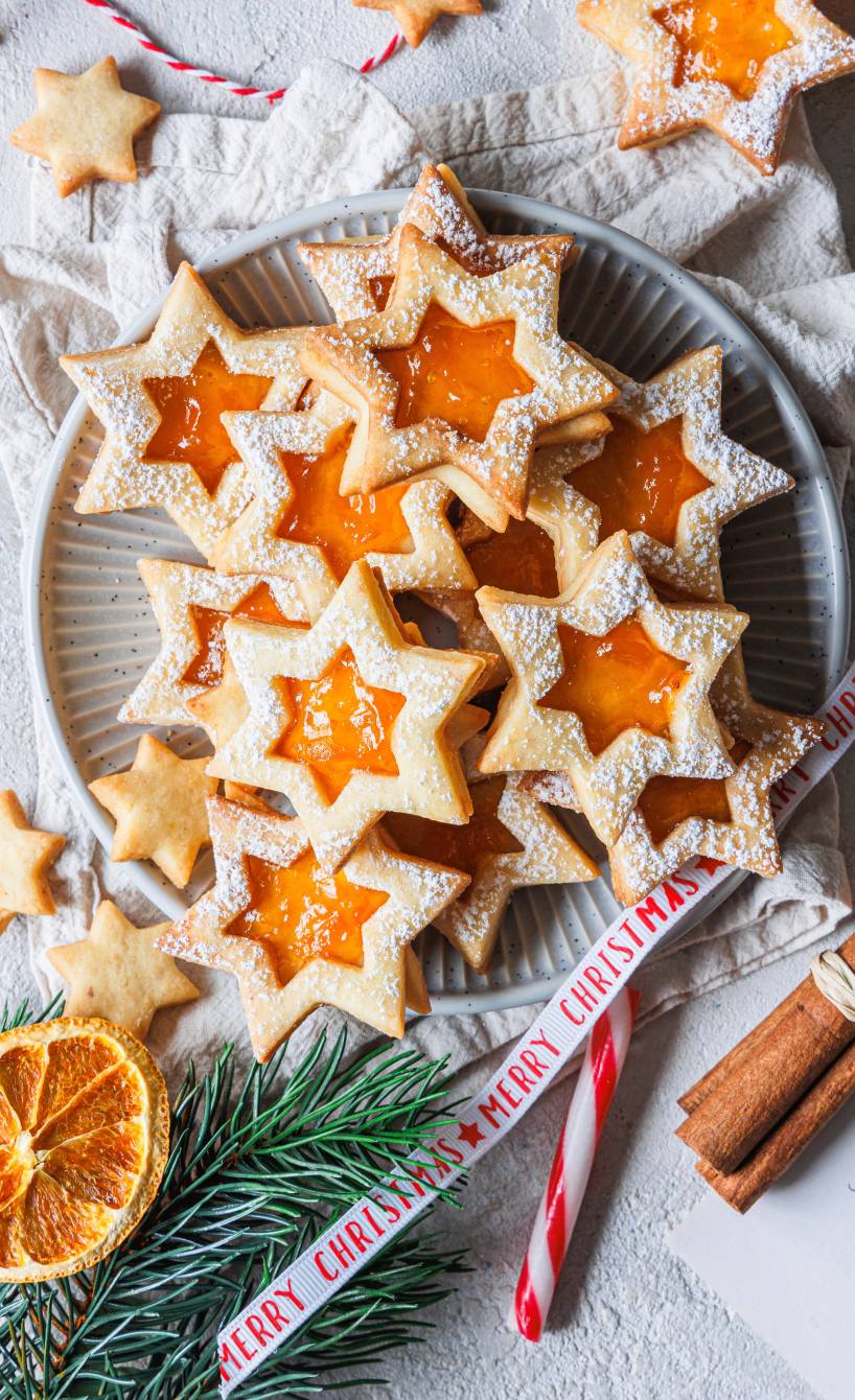 Sternförmige Mürbeteigplätzchen mit Aprikosenfüllung auf einem Weihnachtsteller