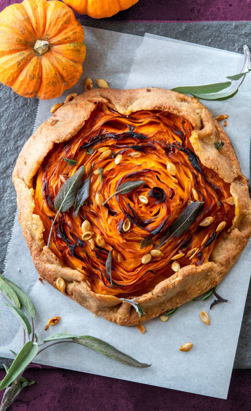 Crostata mit Kürbisfüllung von oben auf einem Tisch, darauf Kürbiskerne als Topping