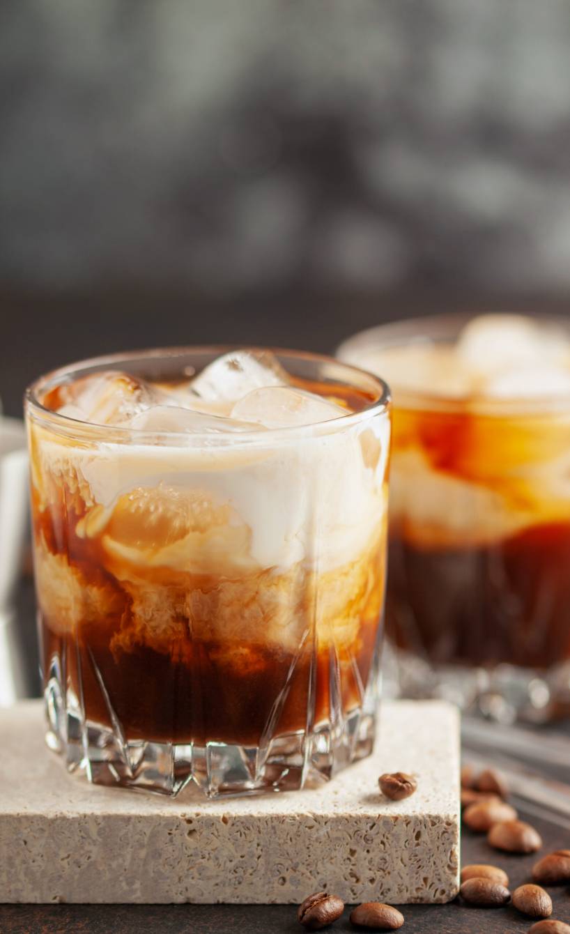 Kaffee-Cocktail mit Sahne und Eiswürfeln in zwei Cocktailgläsern auf einem Tisch
