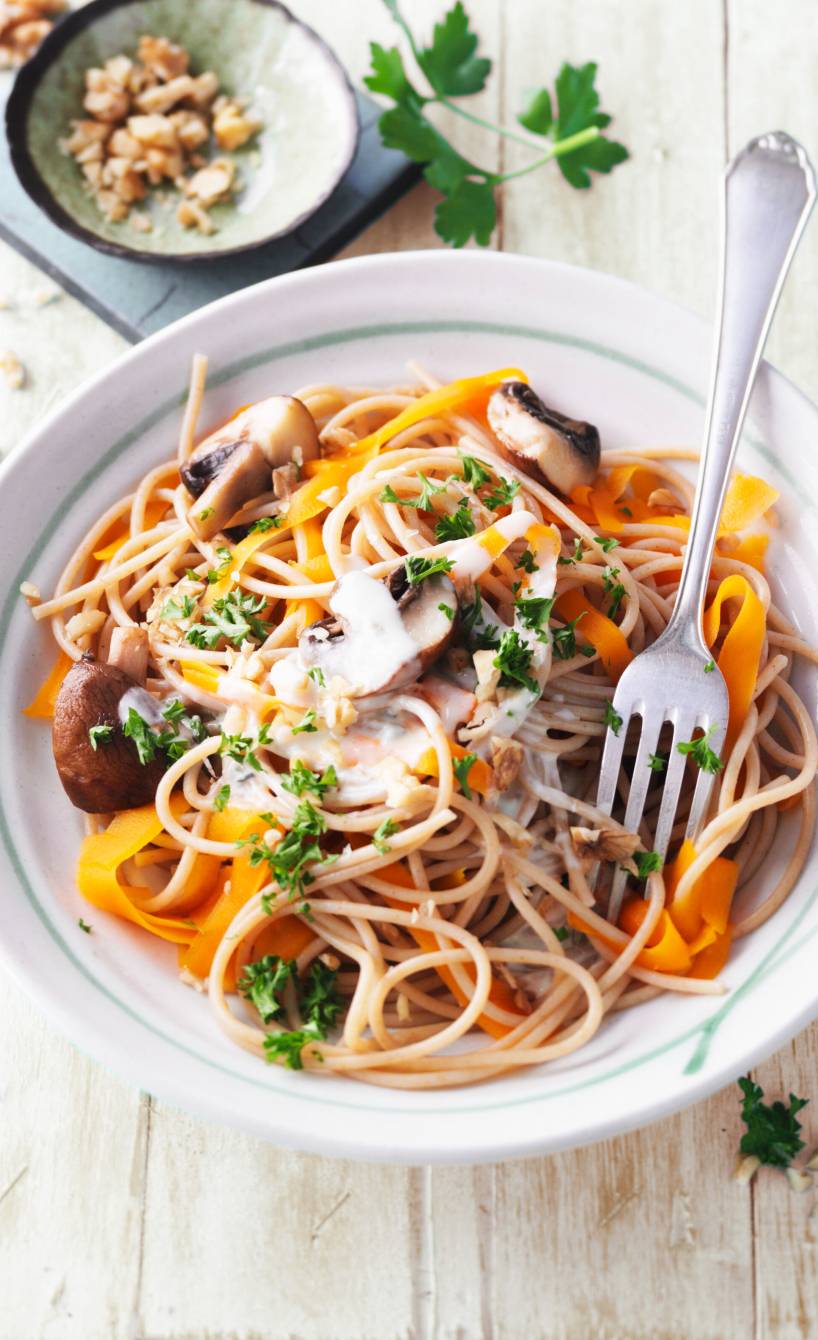 Vollkornspaghetti mit Karotten, Pilzen und Gorgonzola-Sahnesoße angerichtet auf einem Pastateller