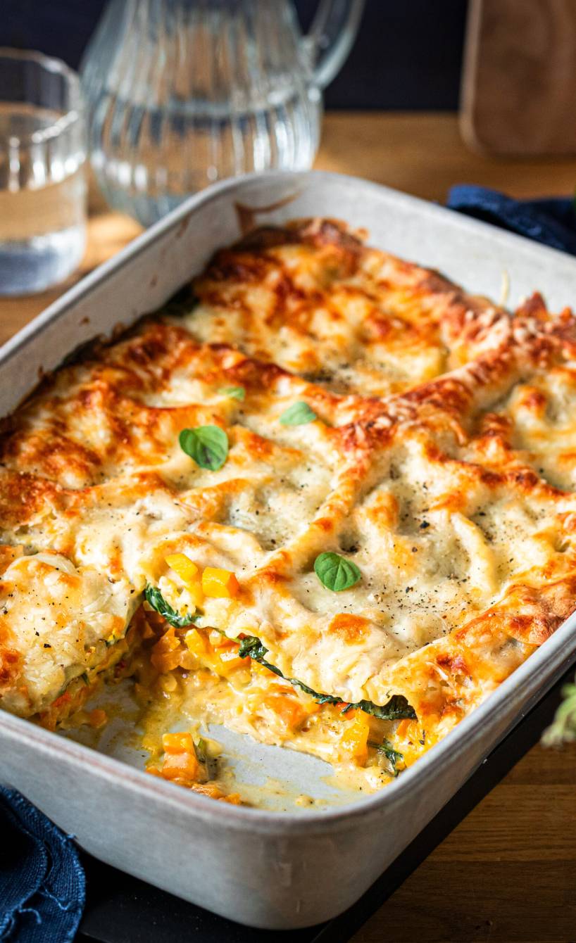 Kürbislasagne mit Spinat und Mozzarella angeschnitten in einer Auflaufform
