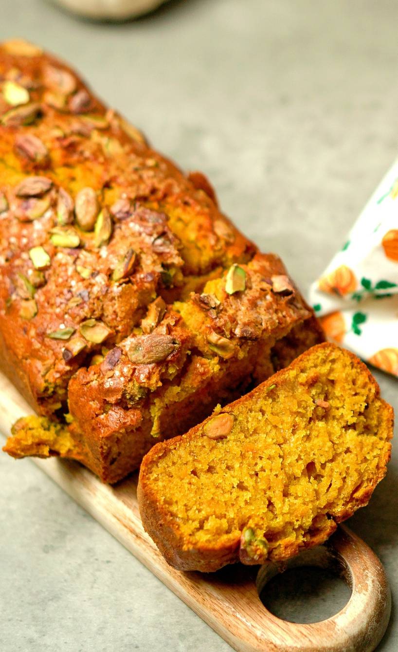 Selbst gebackenes Kürbisbrot mit Pistazien getoppt angeschnitten auf einem Holzbrett