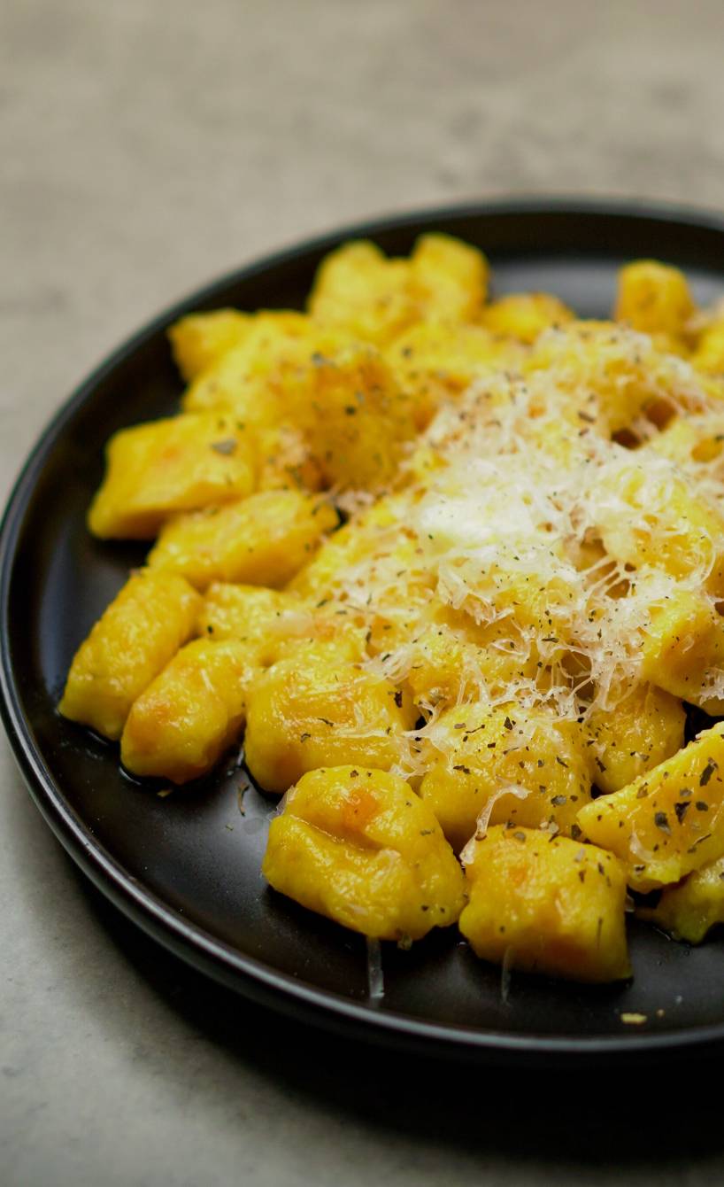 Selbstgemachte Kürbisgnocchi auf einem Teller bestreut mit Parmesan