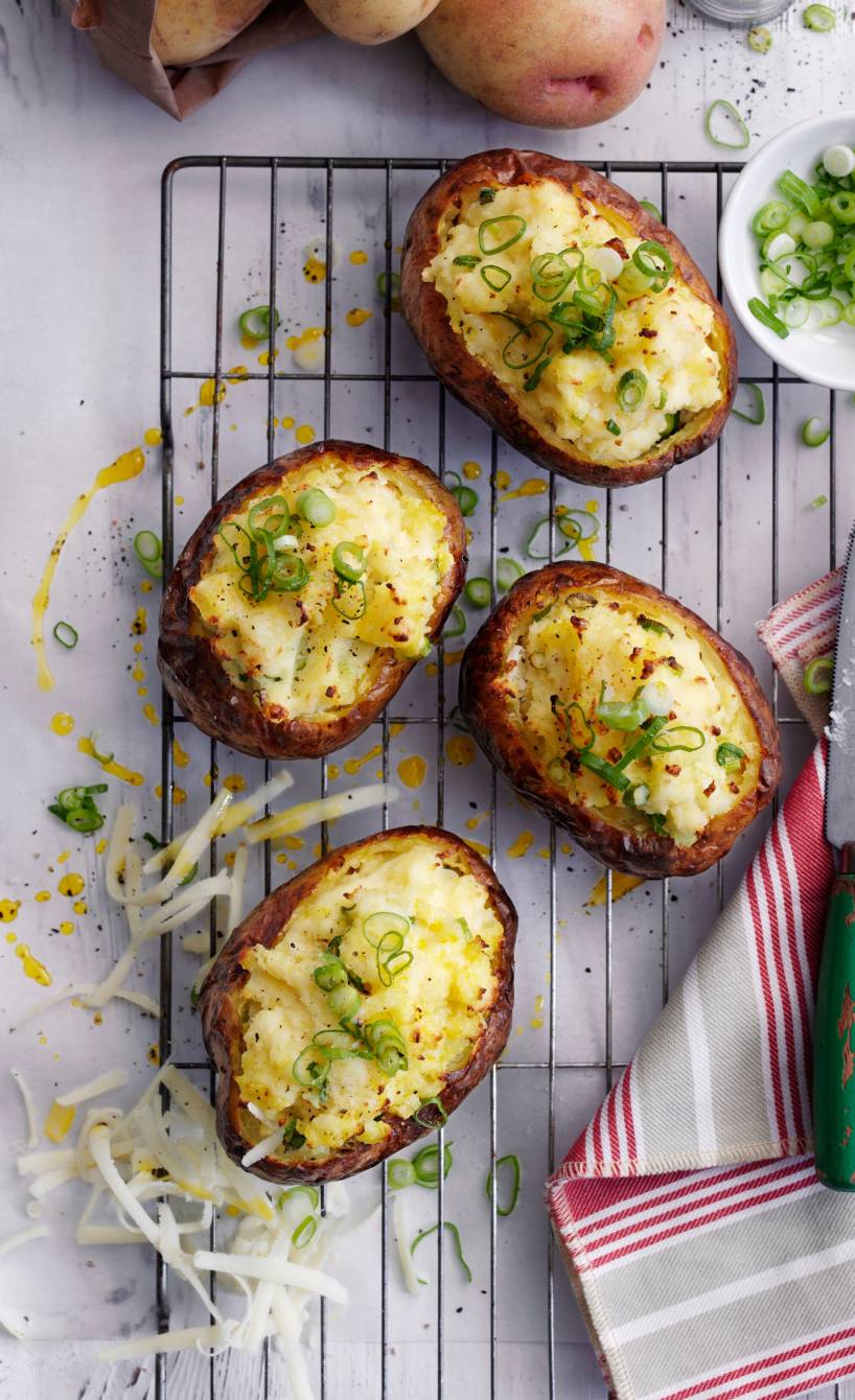 Gebackene Ofenkartoffeln mit Käsefüllung und Frühlingszwiebelröllchen auf einem Backrost