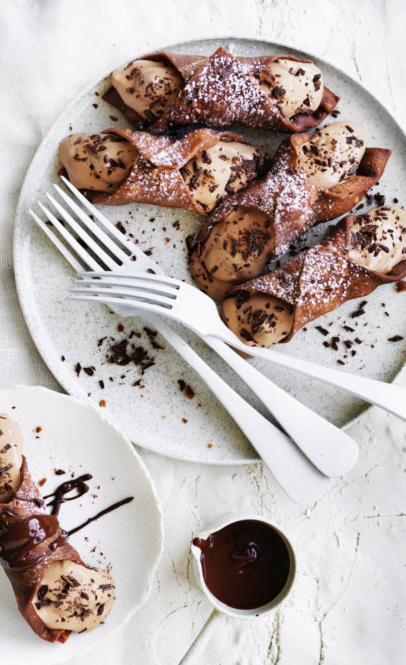 Selbst gemachte Schoko-Cannoli gefüllt mit Ricotta-Schokocreme-Füllung auf einem Dessertteller