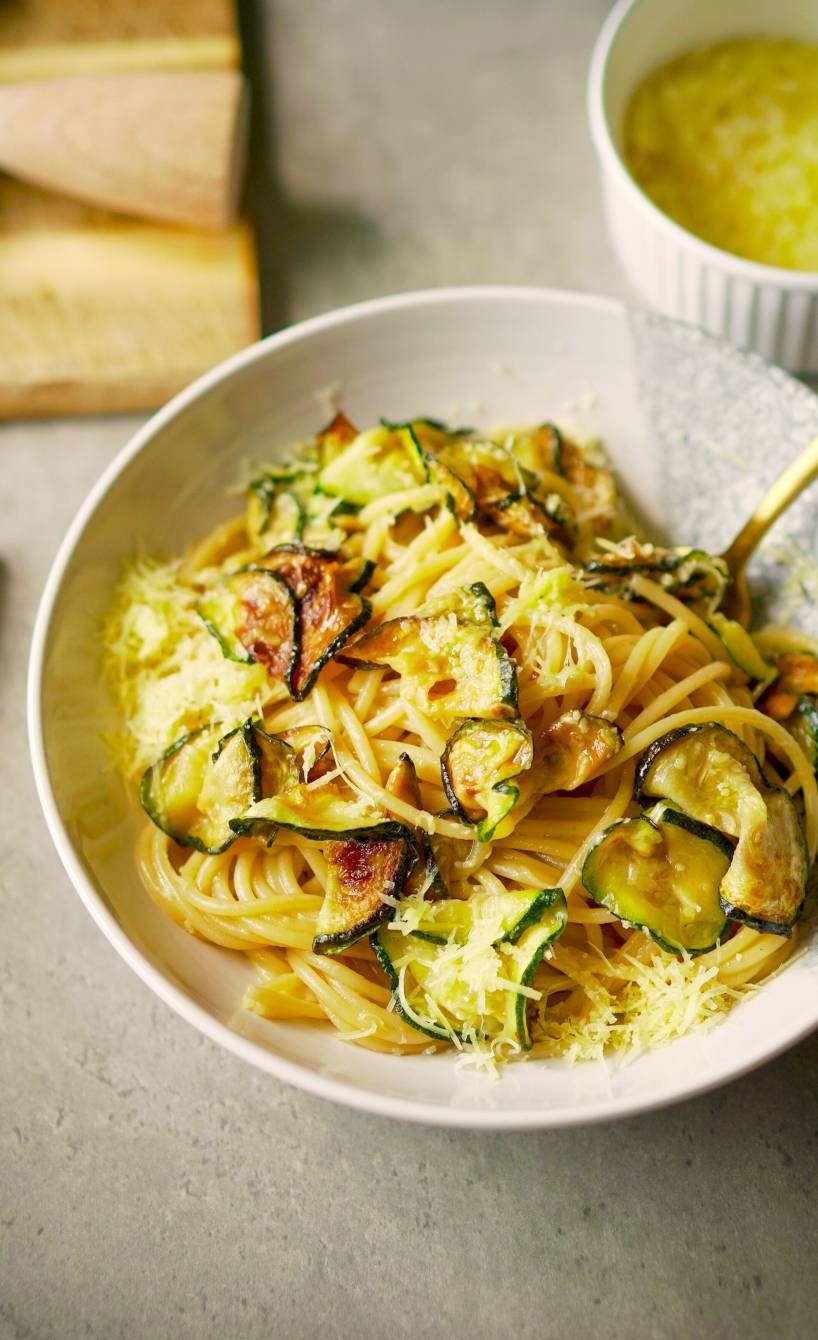 Spaghetti alla Nerano mit Zucchinischeiben und Parmesan in Sauce auf einem tiefen Teller