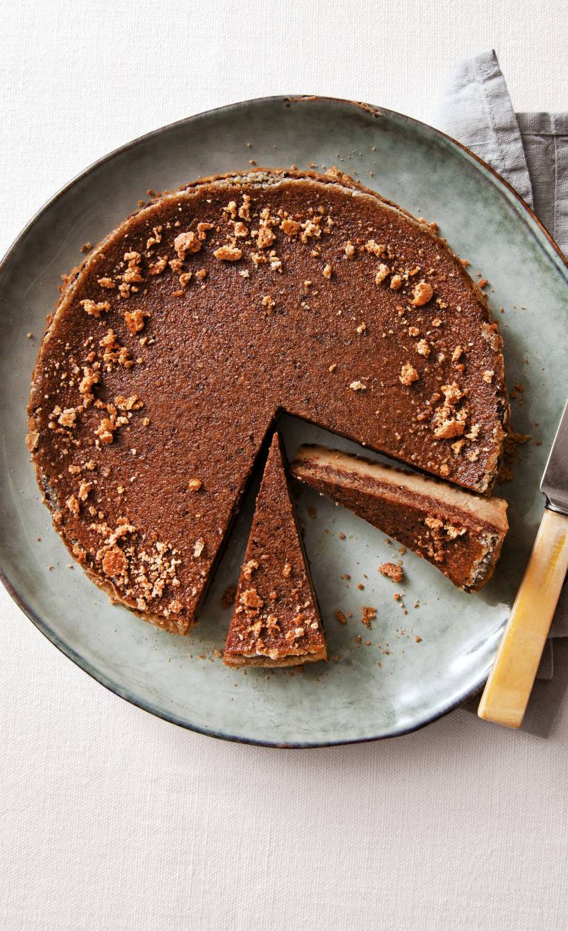Runder Schokoladenkuchen mit Schichten angeschnitten auf einer Kuchenplatte verziert mit Amarettini-Krümeln